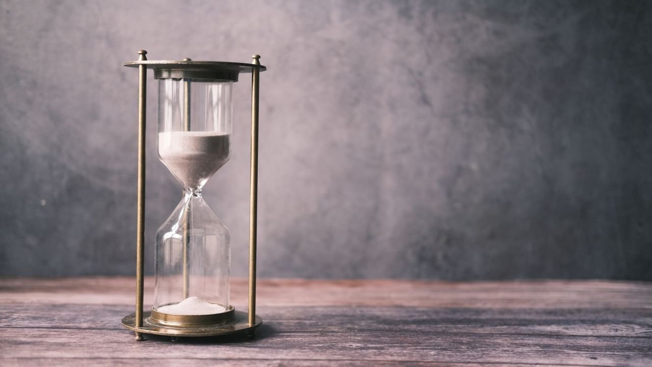 An hourglass with sand on a wooden table