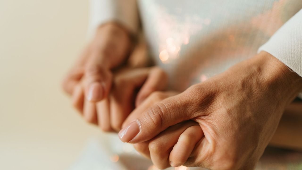 Two hands gently holding each other, close up
