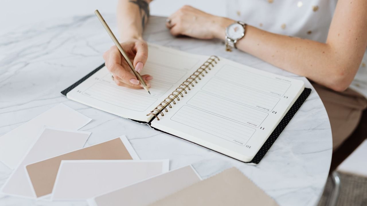 A woman writing in a planner at a table