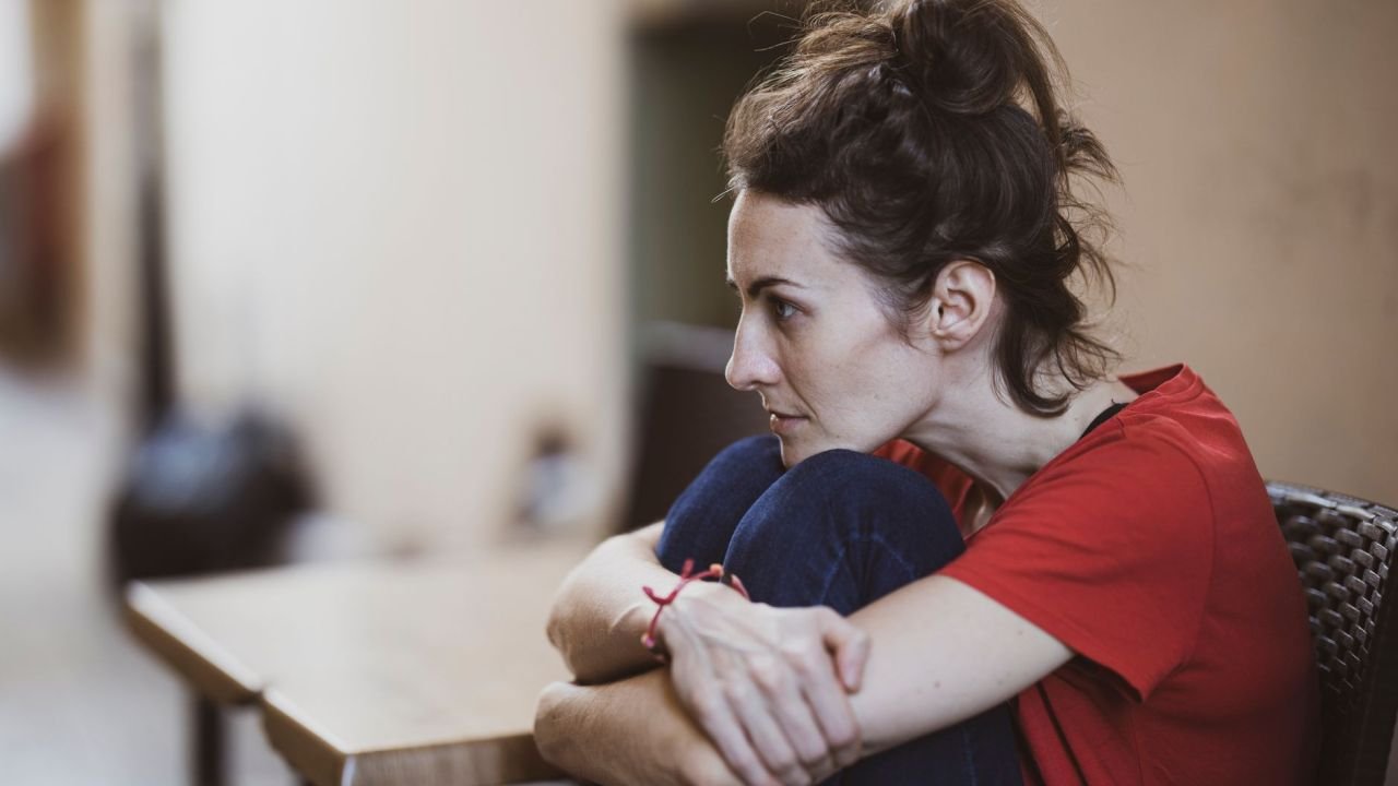 A woman sitting indoors, deep in thought