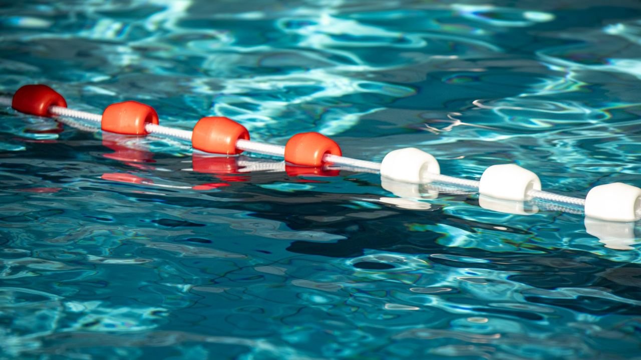 A lane divider floating on sunlit swimming pool water