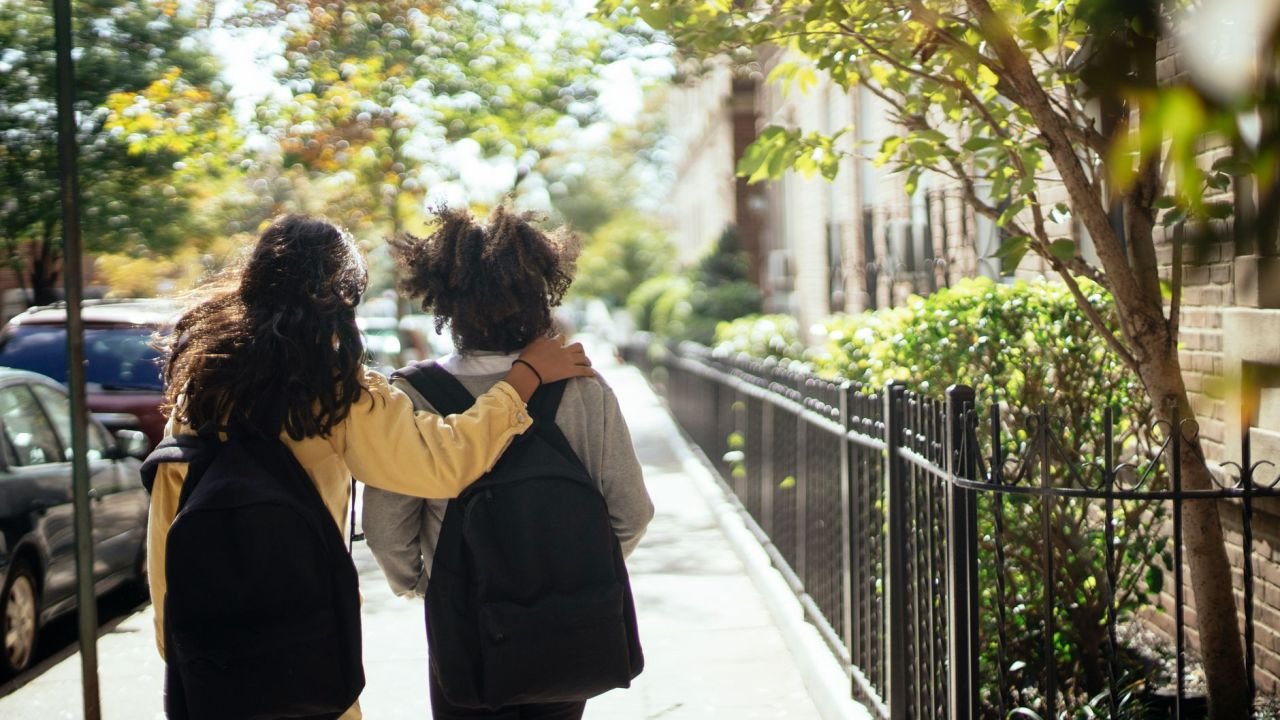 Two girls walking home from school, seen from behind