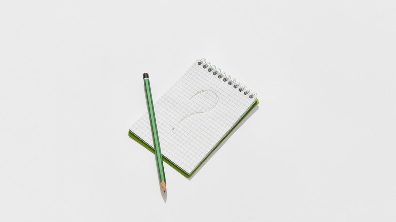 A notepad and pencil with a drawn question mark