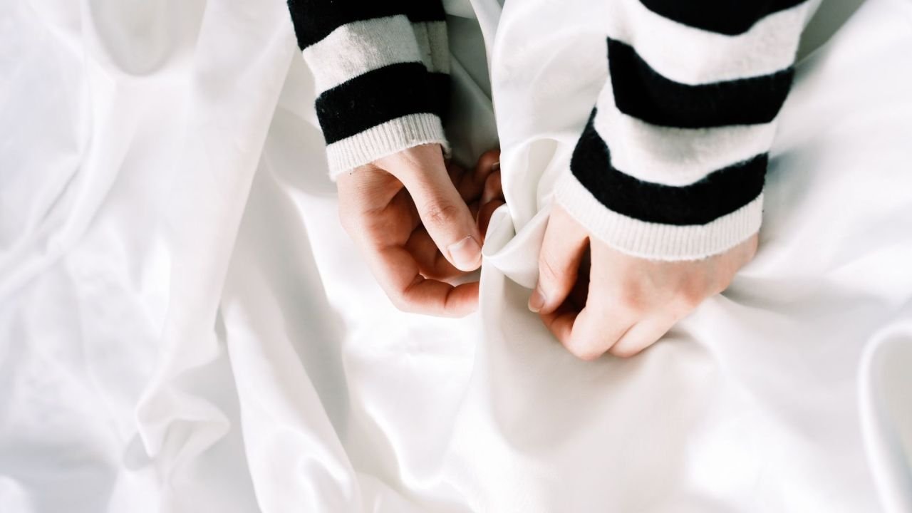 Hands in striped sleeves holding white fabric