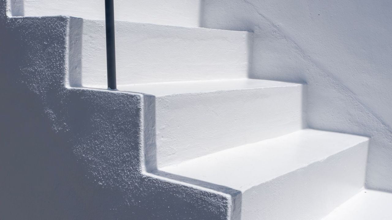 A sunlit white staircase with a railing