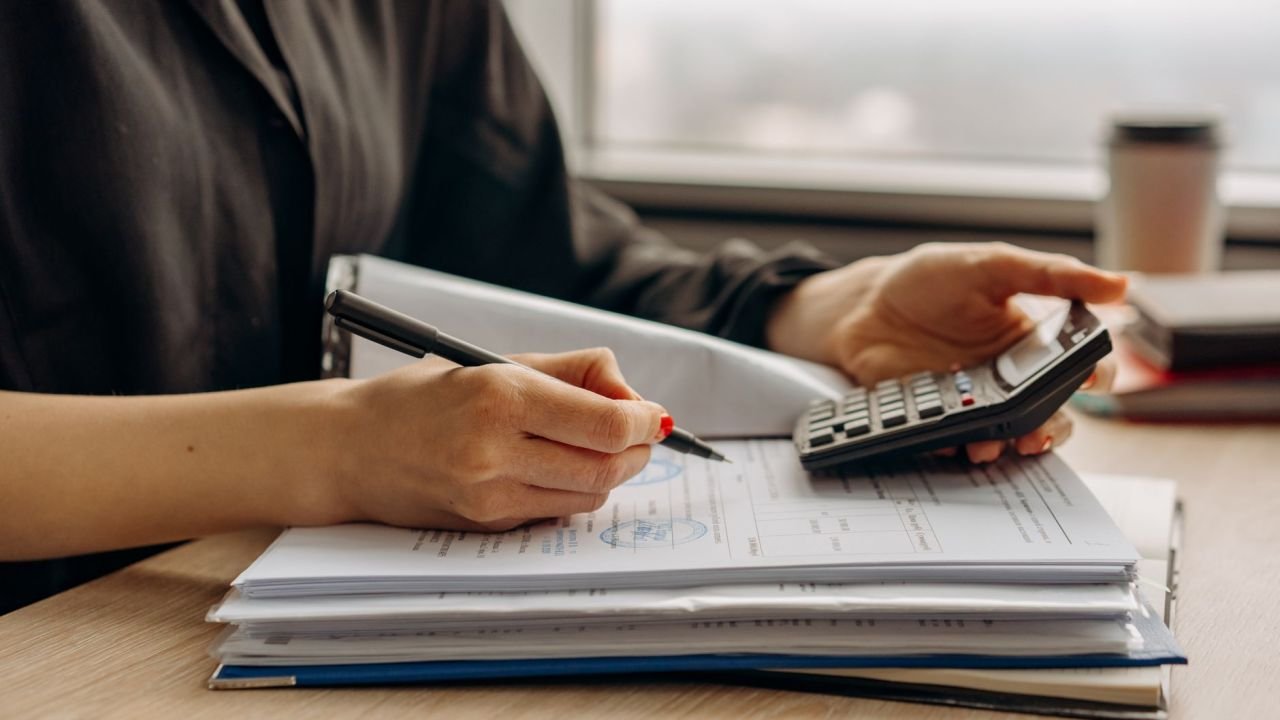 A person using a calculator beside financial documents