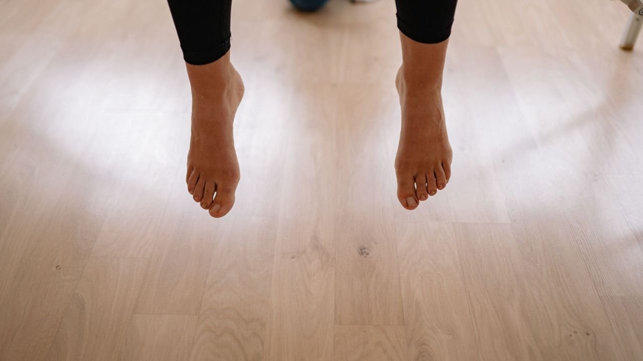 Bare feet above a wooden floor indoors