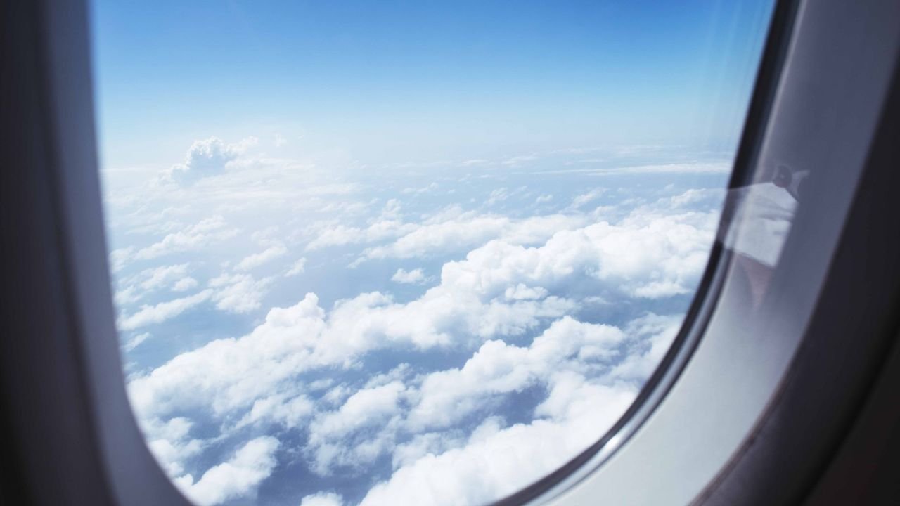 Clouds and blue sky seen through an aeroplane window
